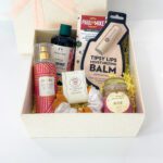 A picture of a white colour personalised mothers day gifts box with delicious chocolate, lip balm, scrunchies etc
