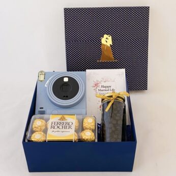 A luxury wedding gift box for groom contains chocolate, a camera, and dry fruits.