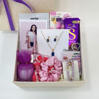 Simple and best rakhi gift for sister, adorned with chocolates, a candle, and accessories
